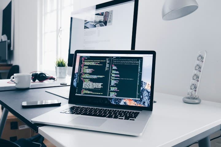 Laptop showing application source code on a bright desk